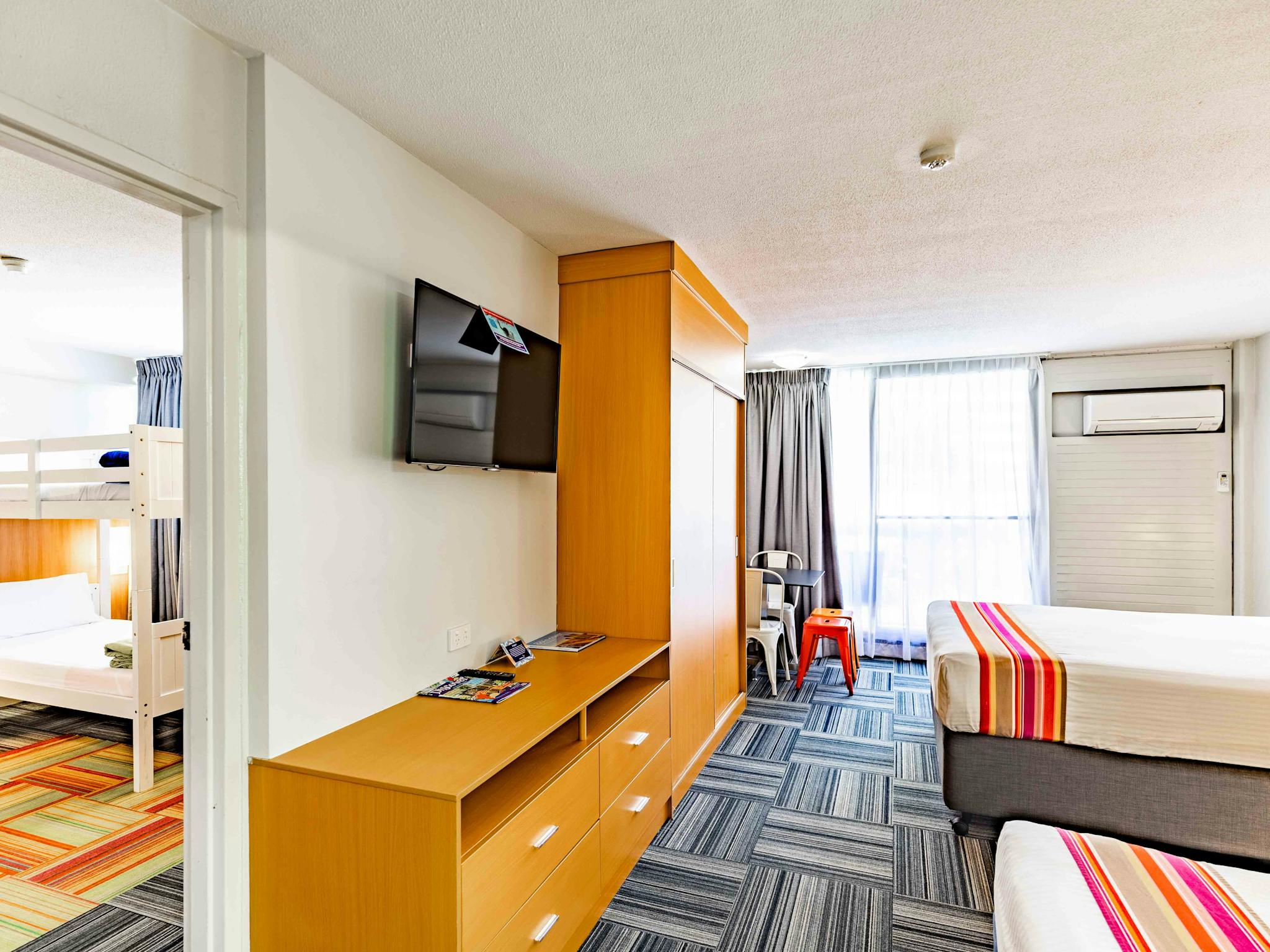 A room with a queen bed and 1 single with an entrance to a second room with white bunk beds A room with a queen bed and 1 single with an entrance to a second room with white bunk beds