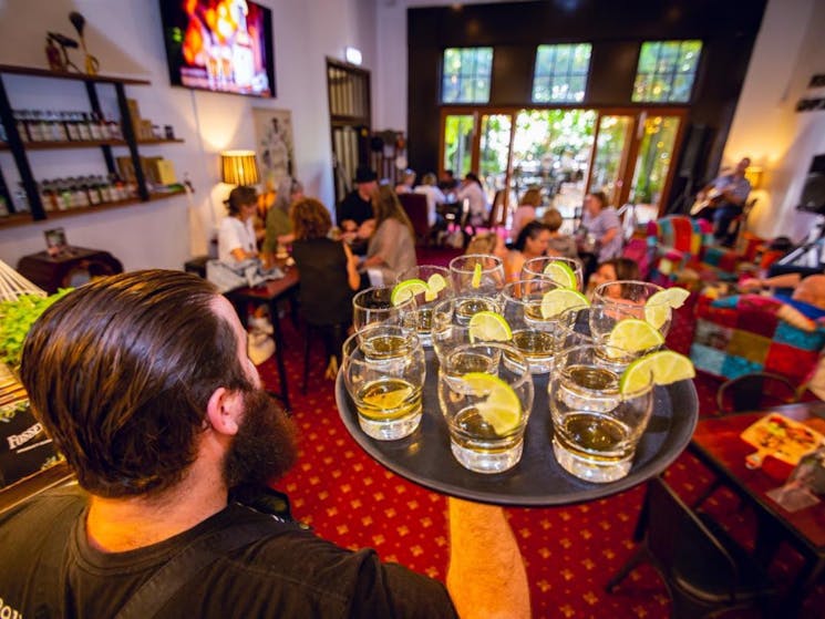 waiter serving gin tasters to customers in Fossey's Distillery