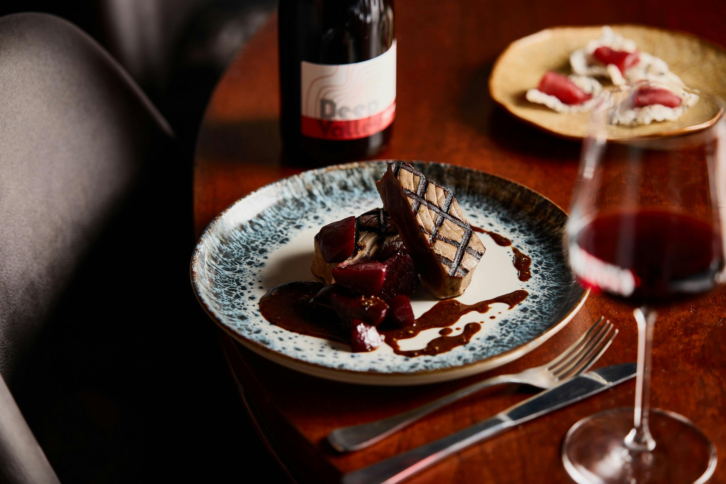 A restaurant dish featuring chargrilled tuna steak, with a glass of Stefano Lubiana pinot noir