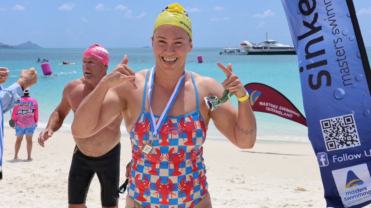 smiling swimmer after being presented with finish medal