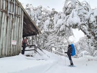 A hiker being greeted by another adventurer into the Bluff Spur Memorial Hut.