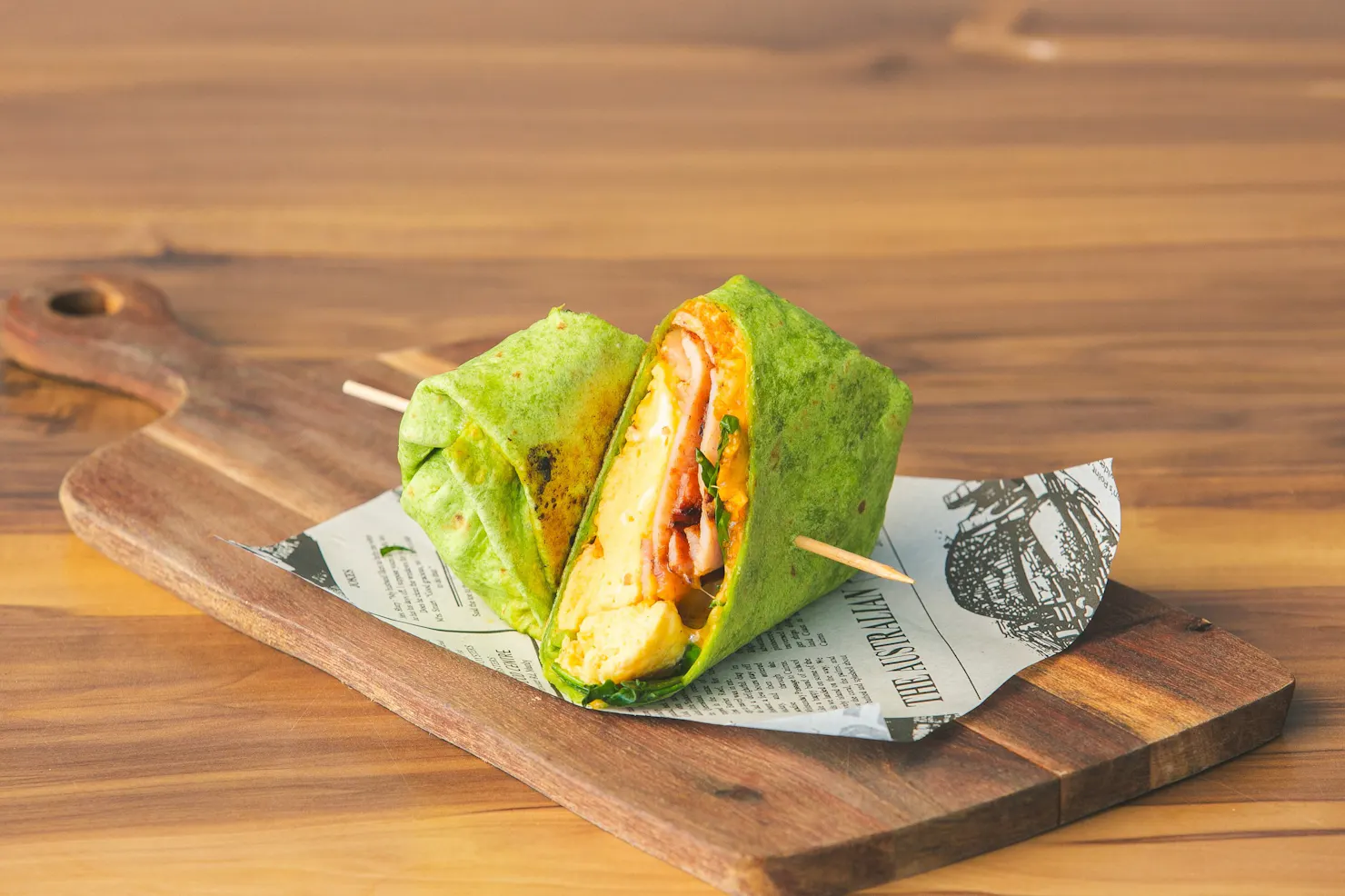 Green brekky burrito with scrambled eggs, bacon, spinach and melted cheese in a spinach tortilla