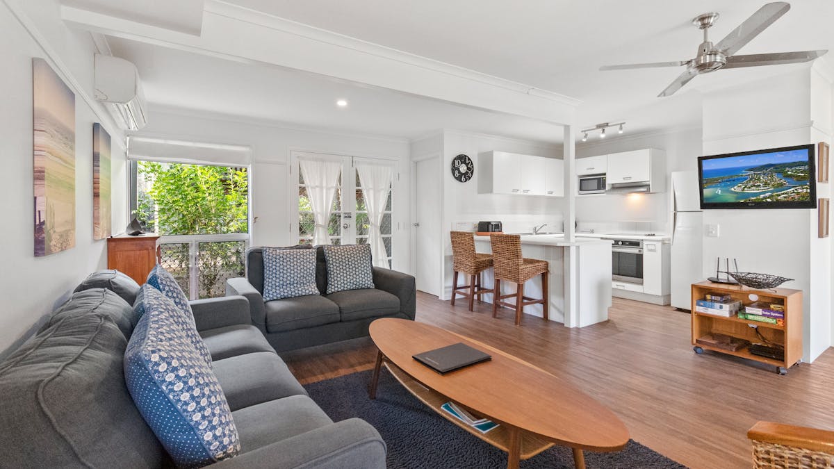 Living room with lounges, coffee table, TV and a view of the kitchen