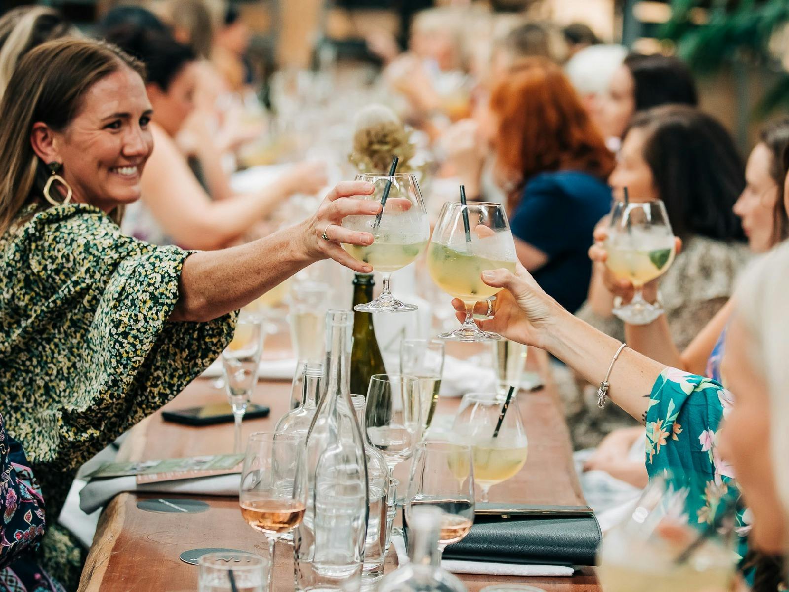 Two women cheers their glasses over a full family-style table