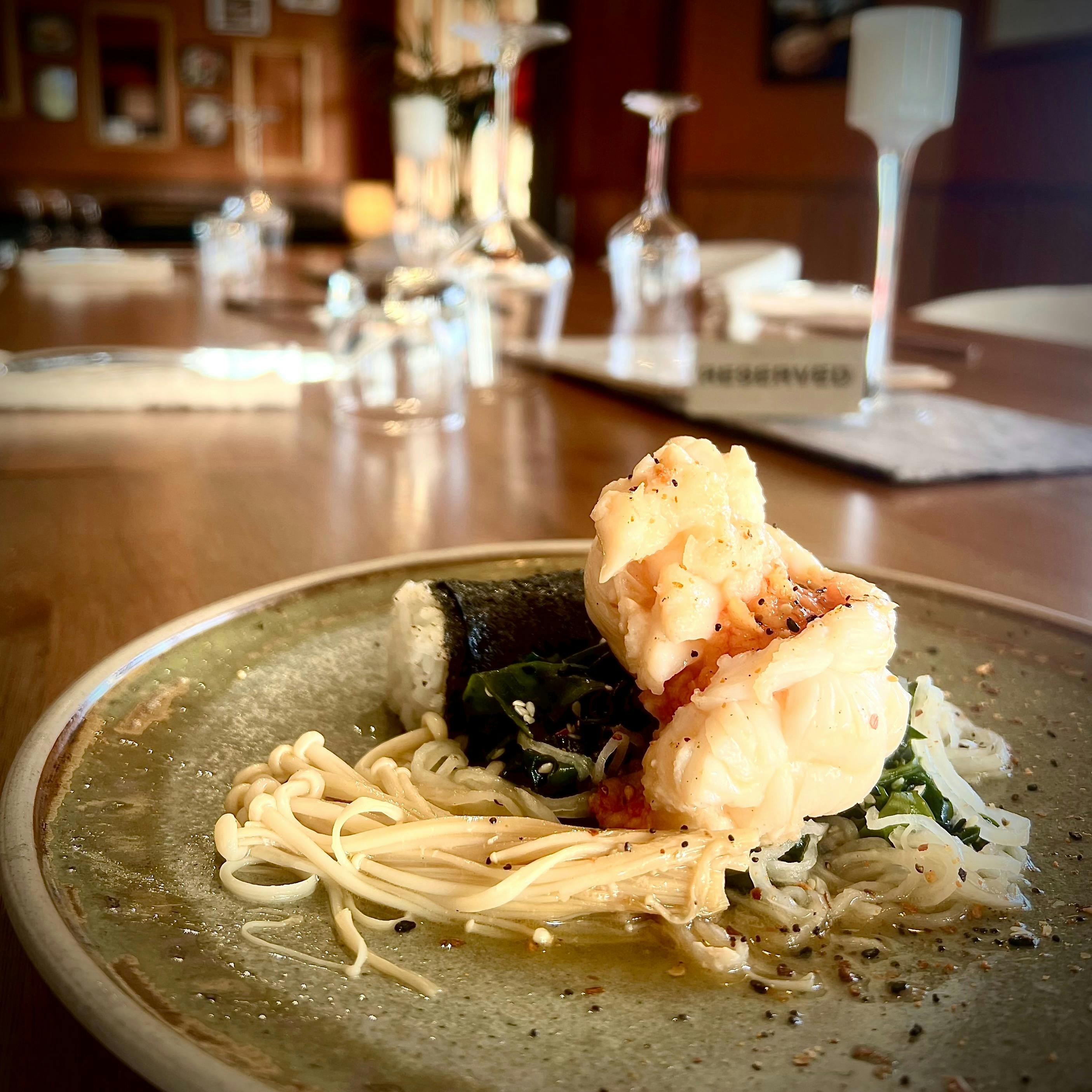 elegant set table with a plate of lobster tail, poached in sake with enoki & onigiri