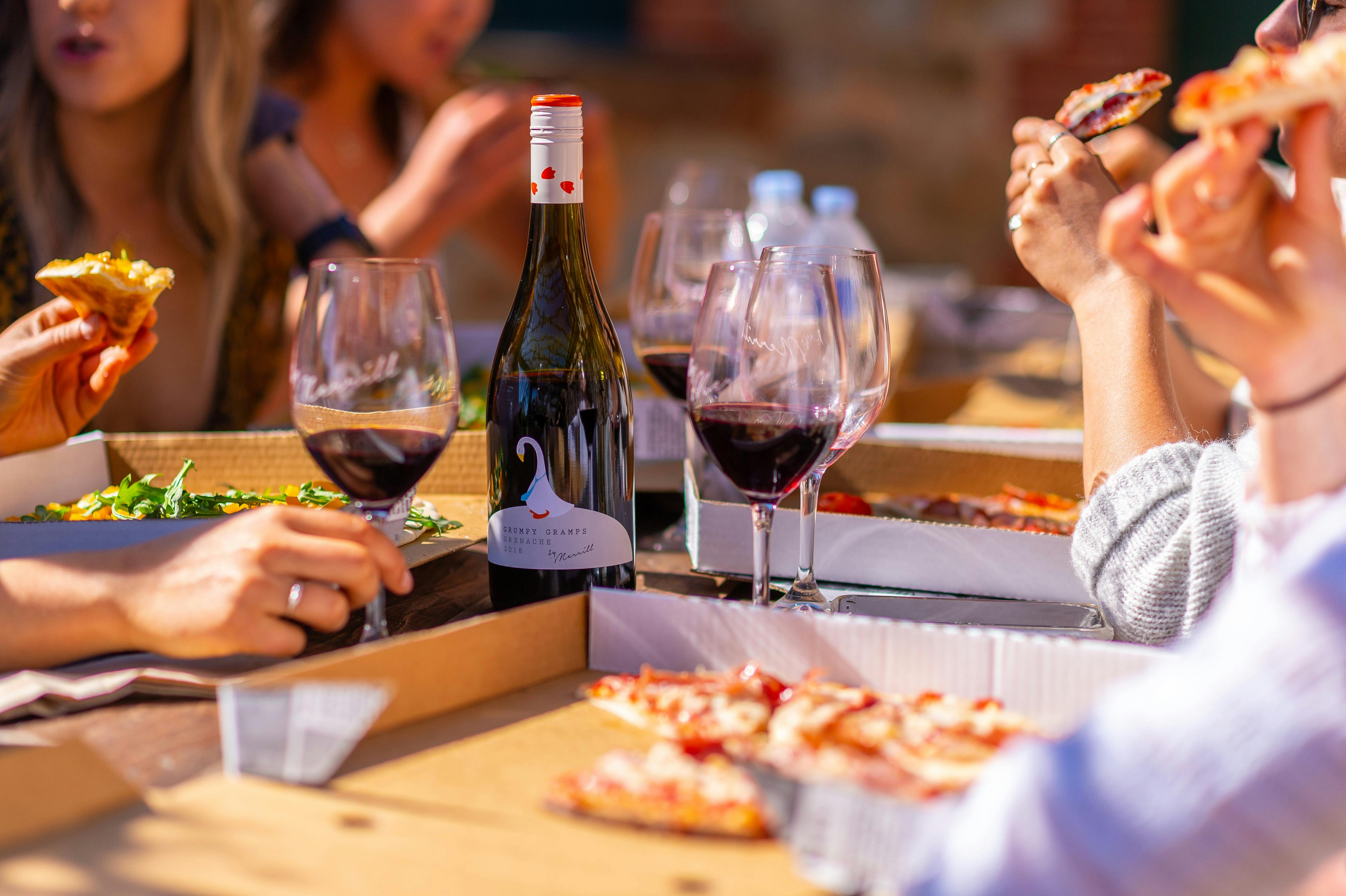 A group enjoying pizza and red wine