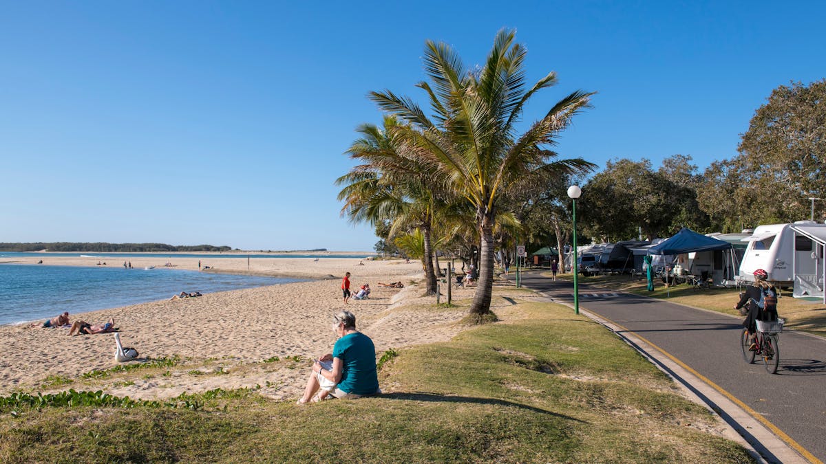 Cotton Tree Holiday Park shot with one side the beach with palm trees and other side with caravans Cotton Tree Holiday Park shot with one side the beach with palm trees and other side with caravans