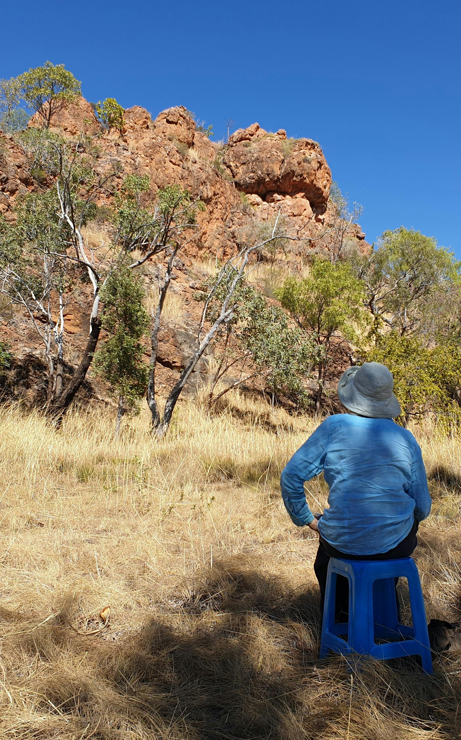 Person seated drawing a rock formation