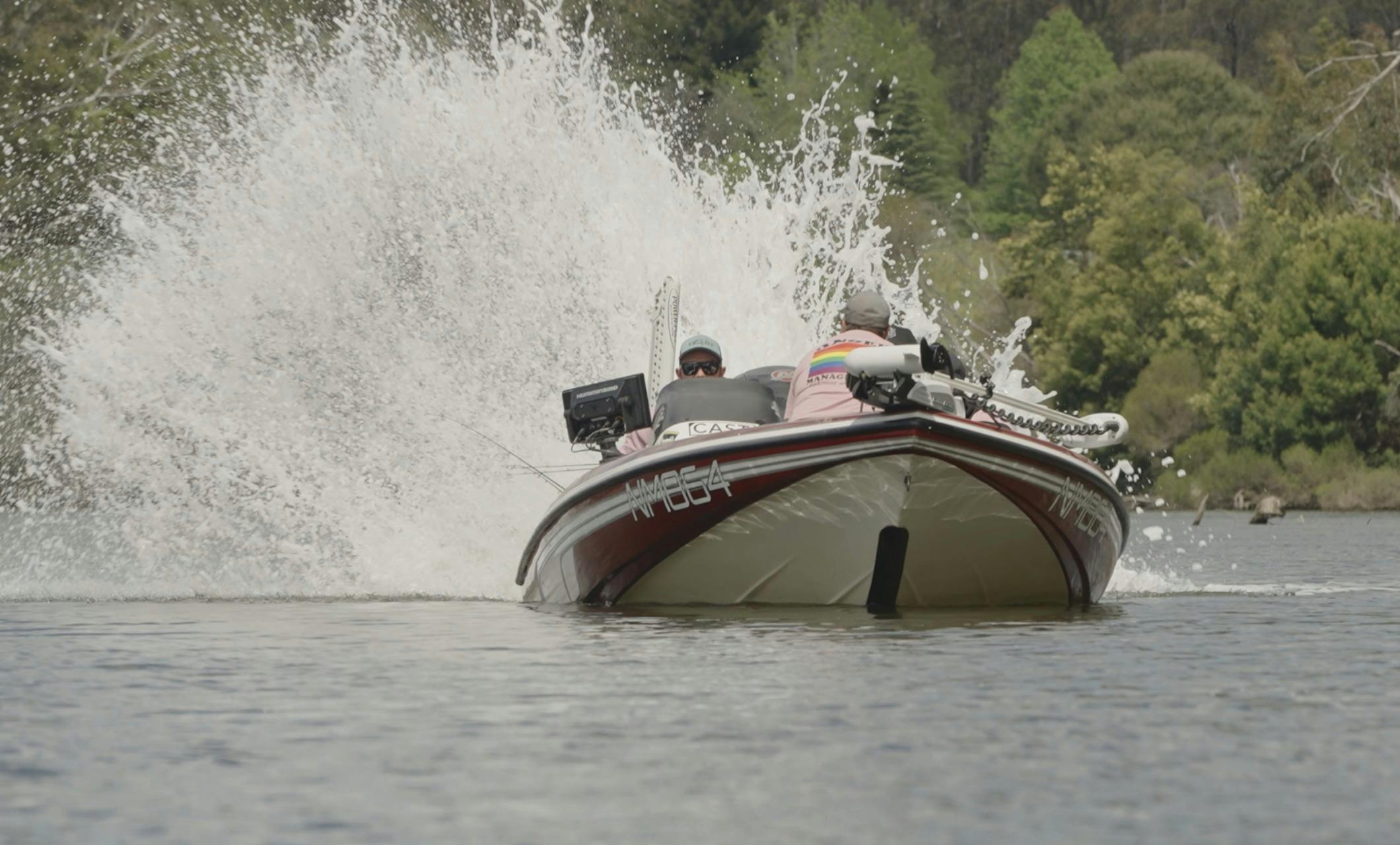 Tournament boat taking off with a huge wall of spray behind it on a calm lake