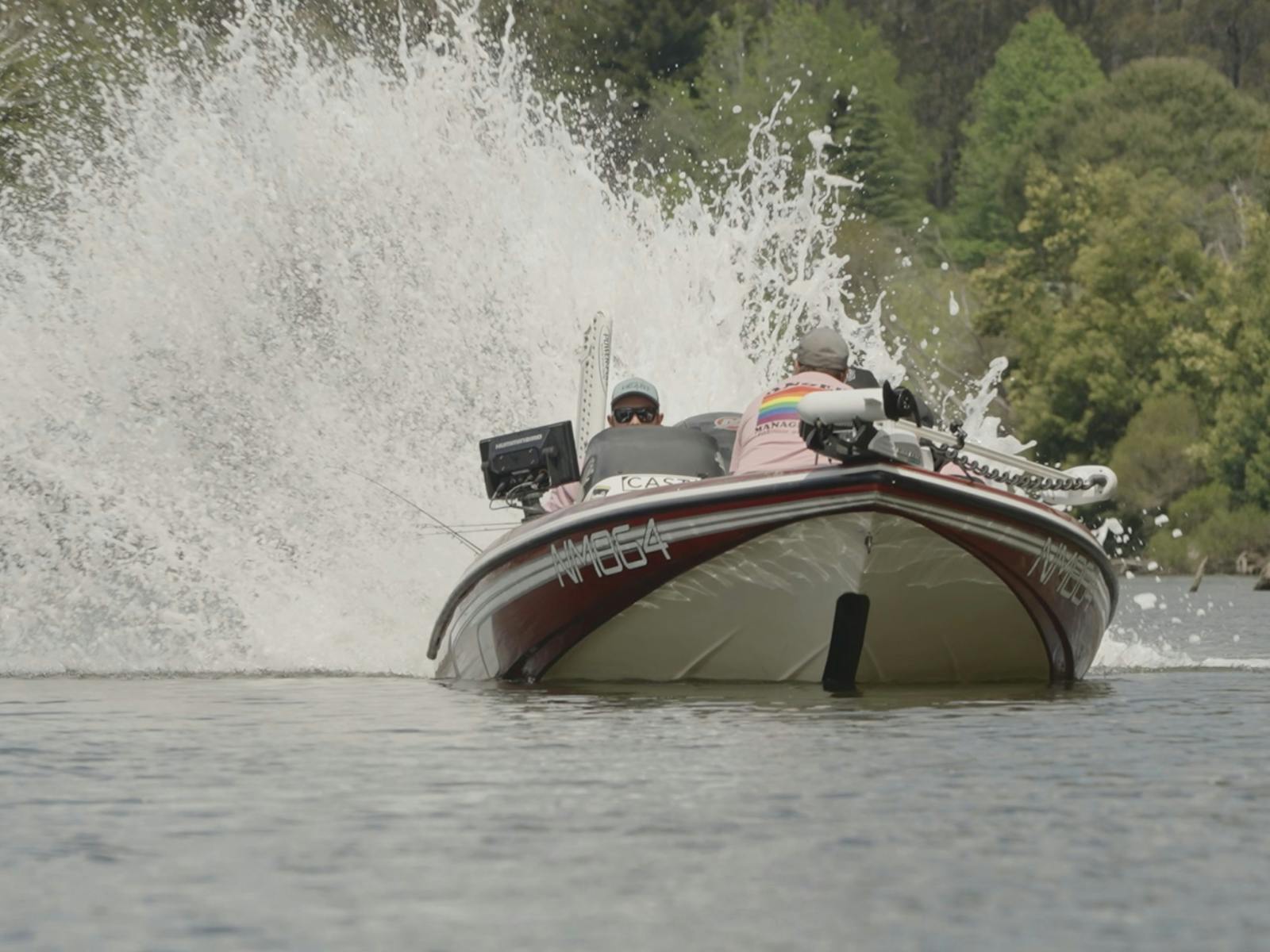 Tournament boat taking off with a huge wall of spray behind it on a calm lake
