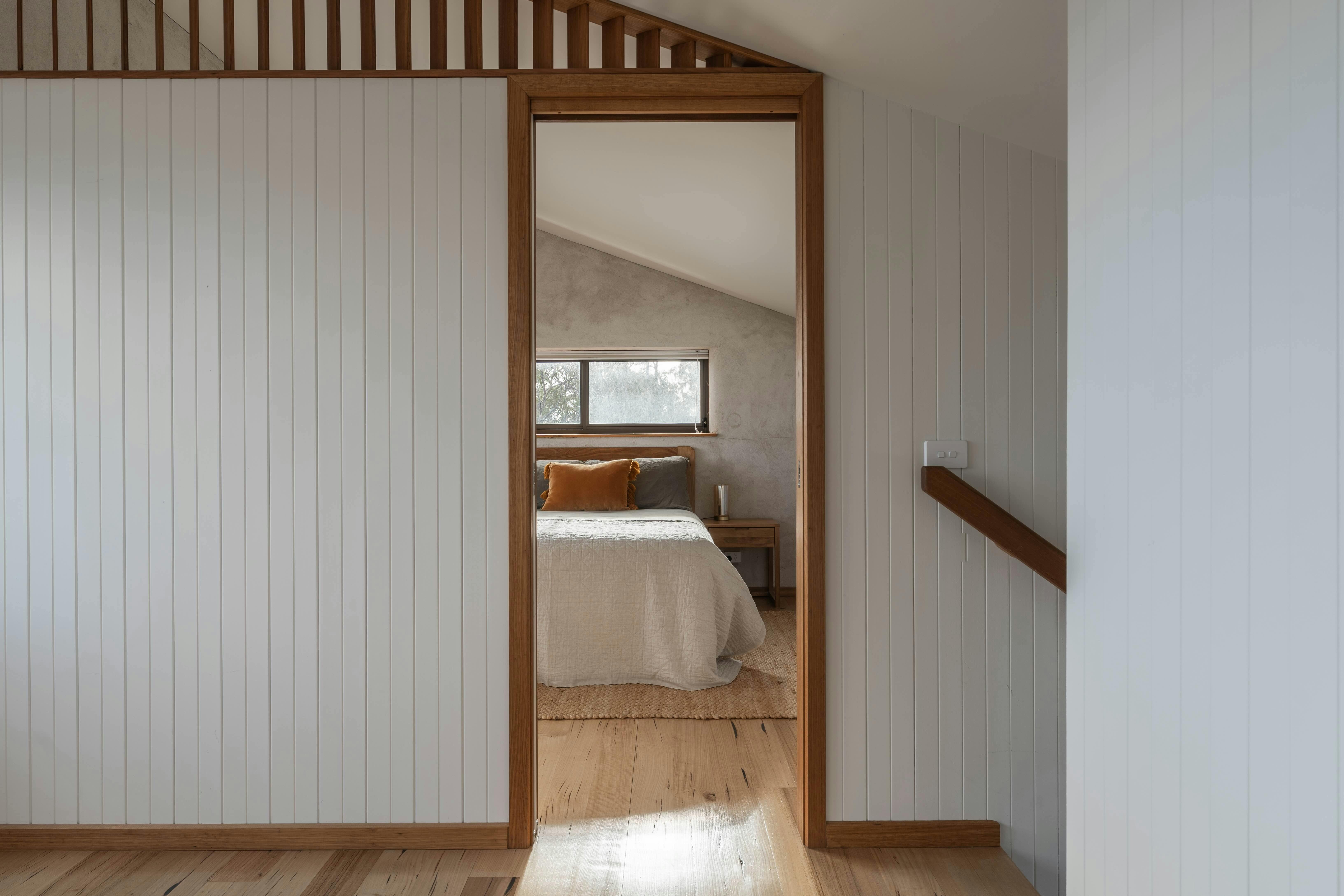 A view through a bedroom door showing a section of the queen sized bed inside.