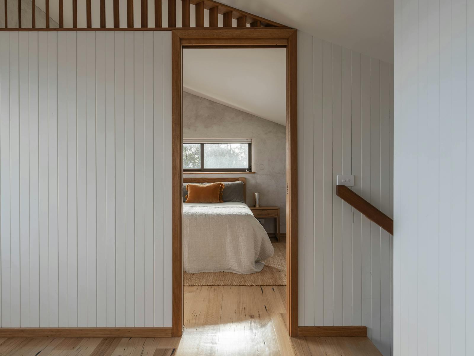 A view through a bedroom door showing a section of the queen sized bed inside.