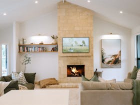 Open plan living room with stone fireplace and seating in ORBE Properties accommodation Robe South A