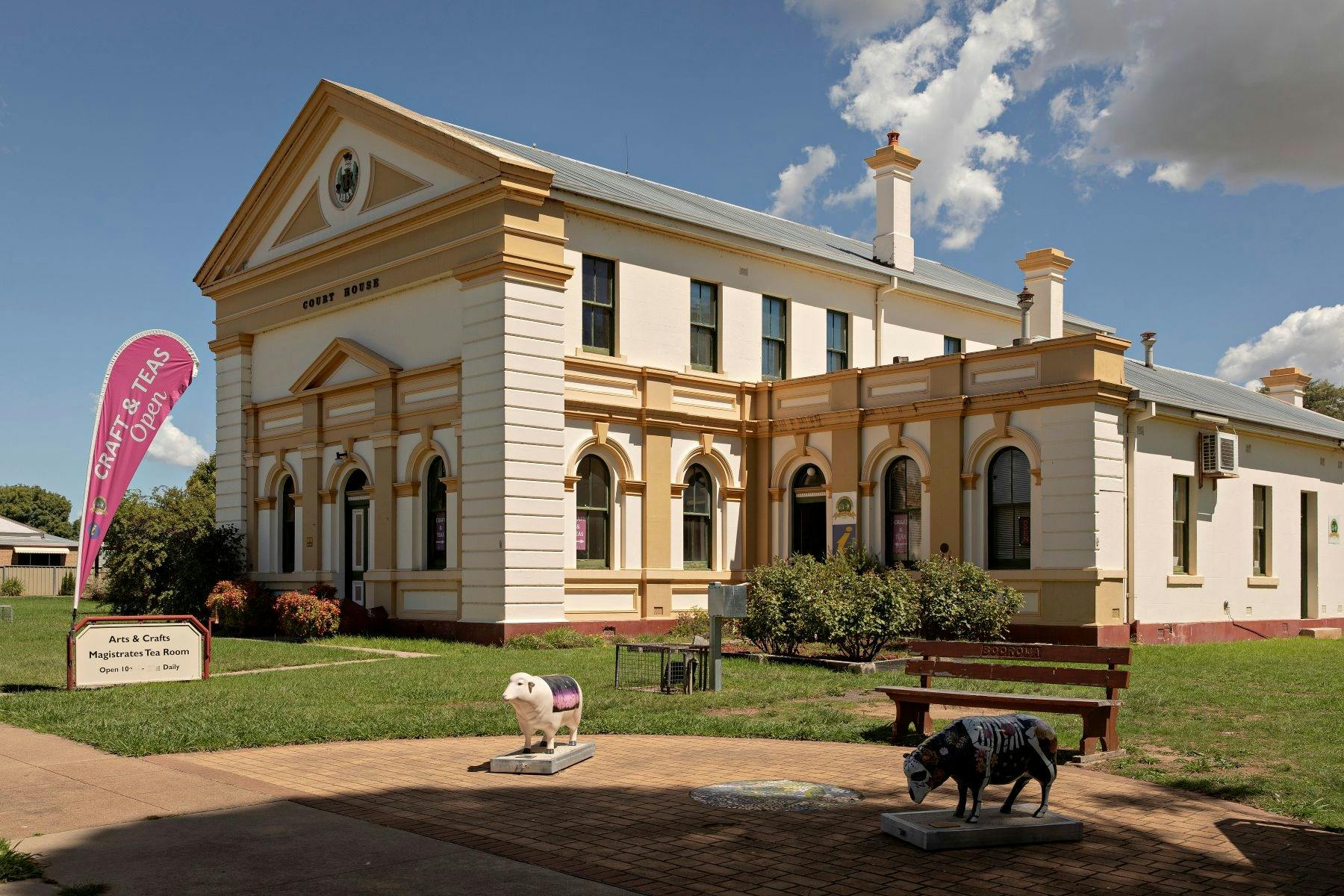 Outside the old courthouse building. Paint sheep statues outside with the open teardrop flag up.