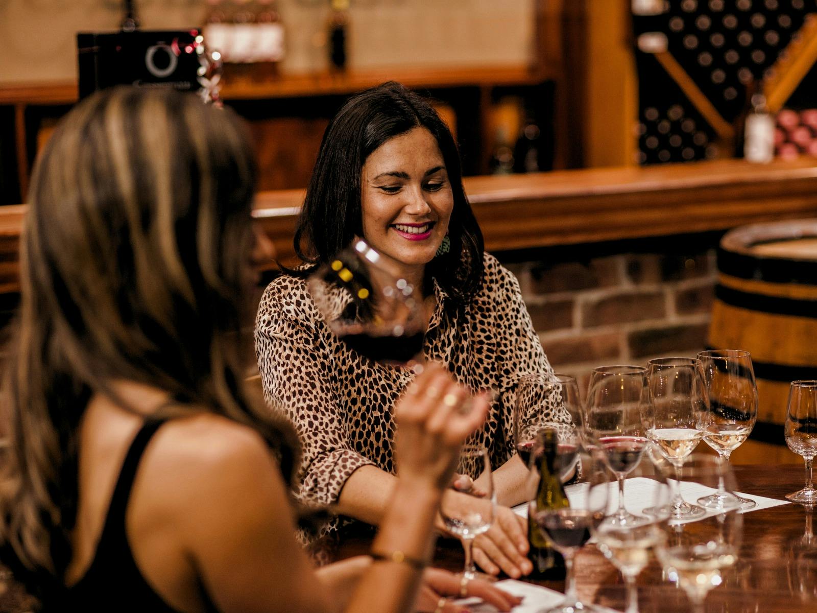 Two women sitting at a table in their cellar door tasting wine