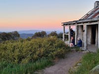 A small group of hikers enjoying sunset from the Craig's Hut front porch.