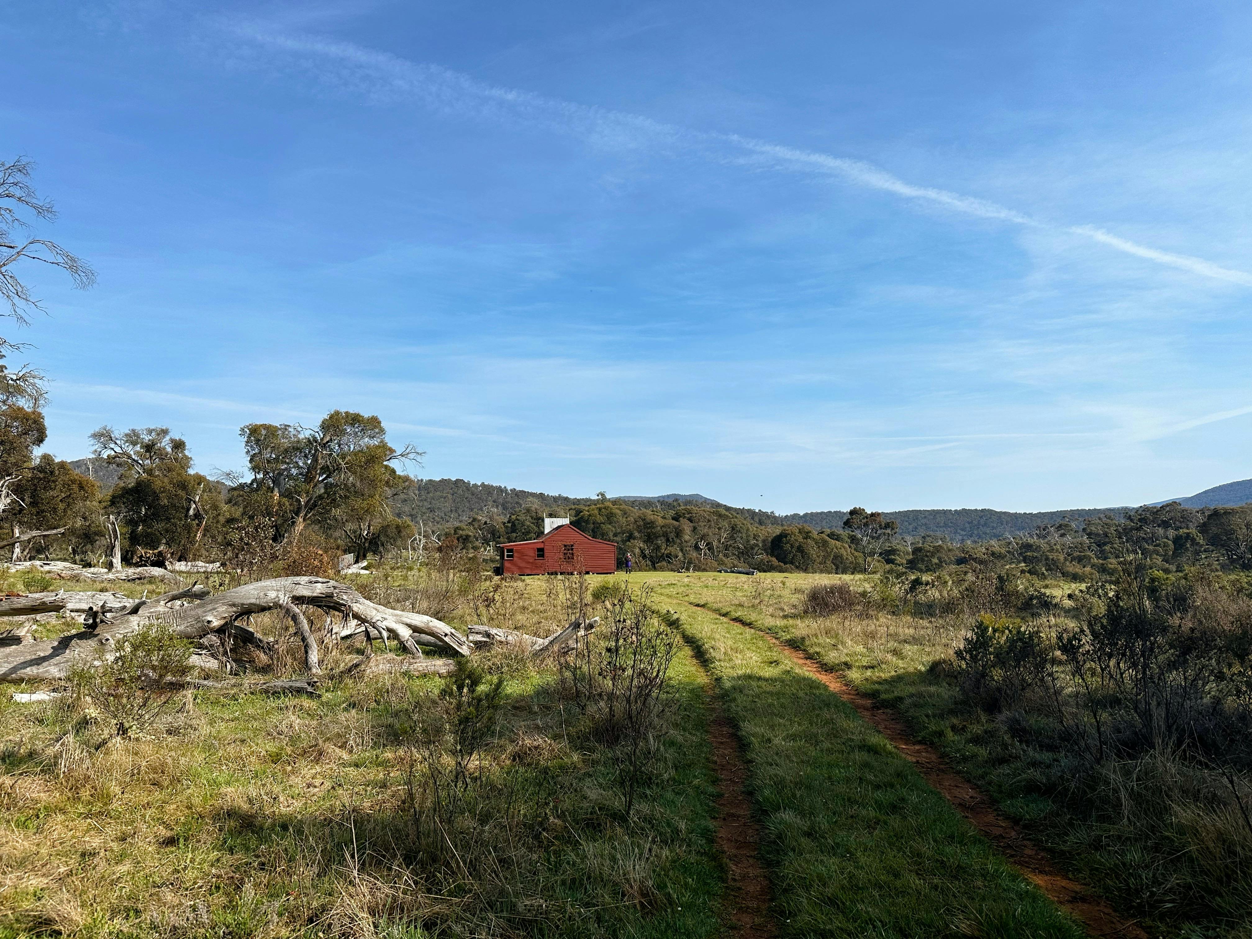 A hut in an open plain with a four wheel drive leading up to it.