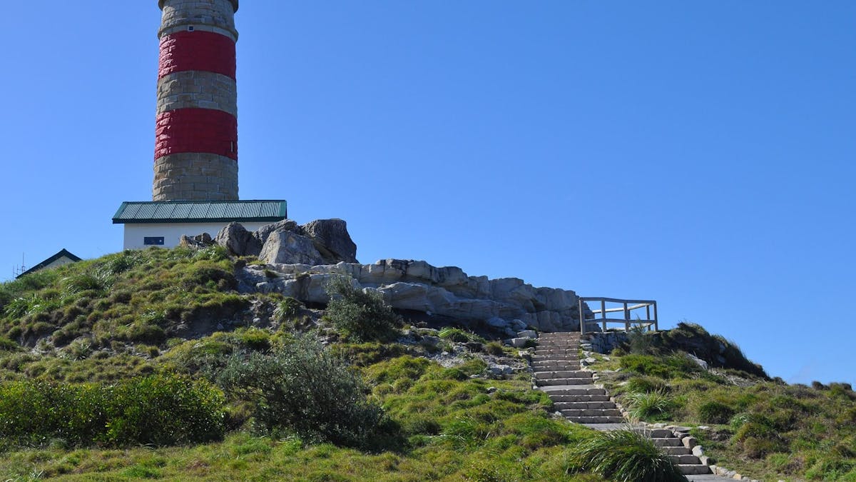 Steps leading up to a red and white striped lighthouse