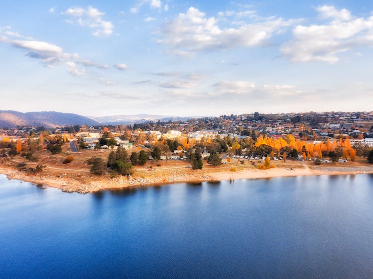 View of a country town with a lake with blue water and yellow Autumn trees