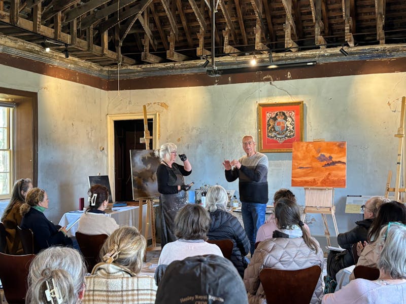 A group of people sit in a historic old building, listening to two people talk
