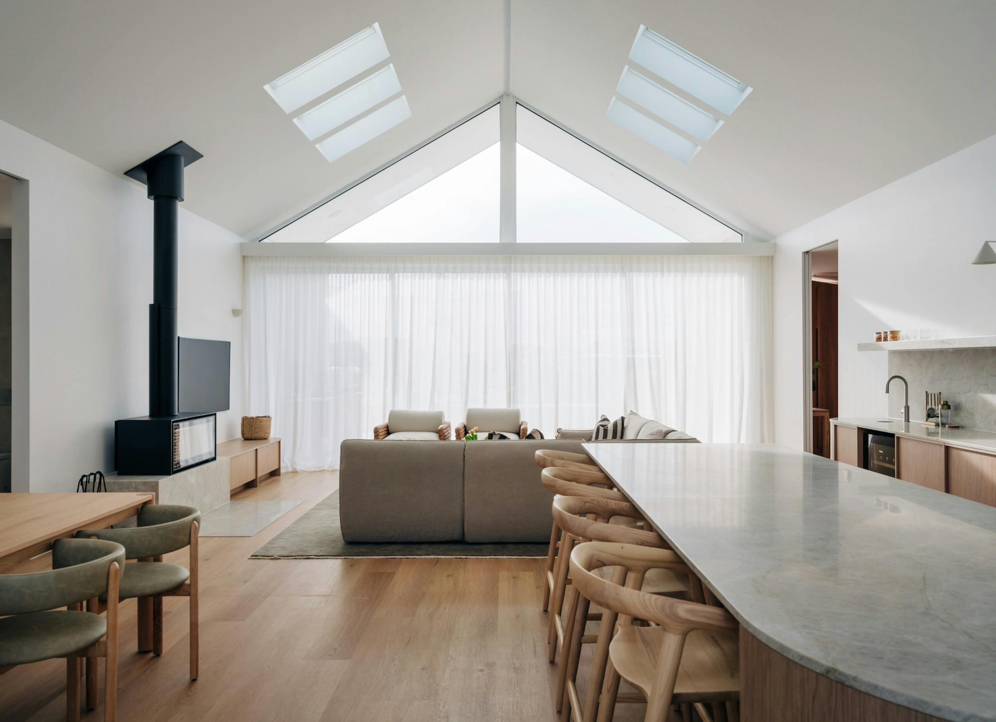 Kitchen, living and dining area with views of large expansive windows with high cathedral ceilings