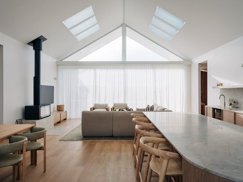 Kitchen, living and dining area with views of large expansive windows with high cathedral ceilings