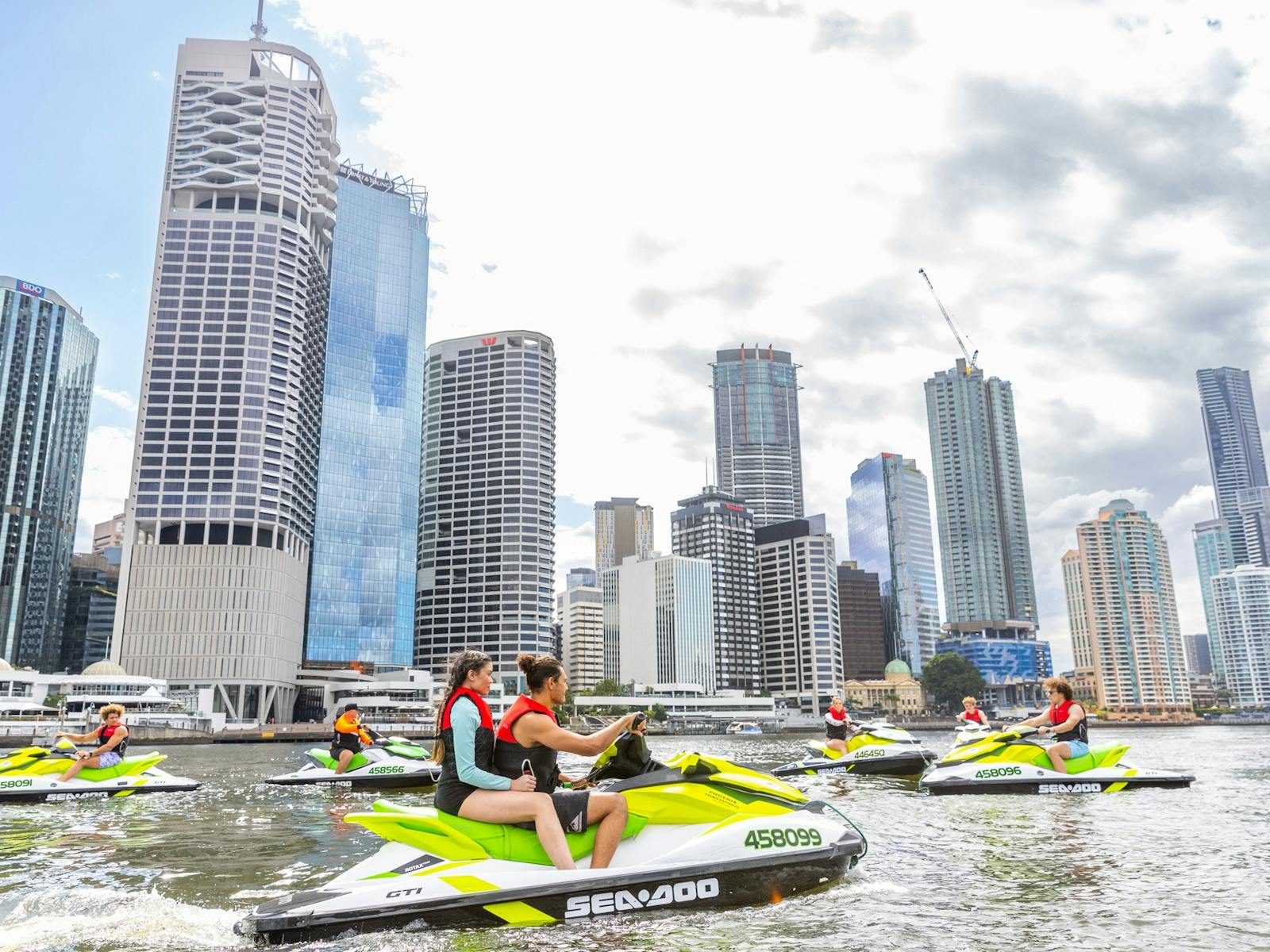 Group of people relaxing on jet skis near Eagle Street Pier with Brisbane City skyline in background Group of people relaxing on jet skis near Eagle Street Pier with Brisbane City skyline in background