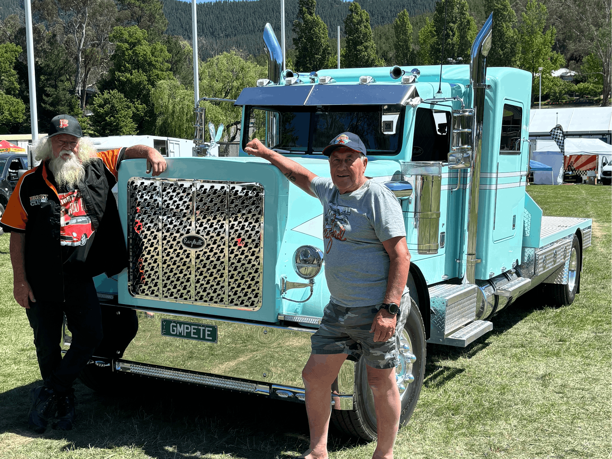Two people standing next to a teal coloured truck