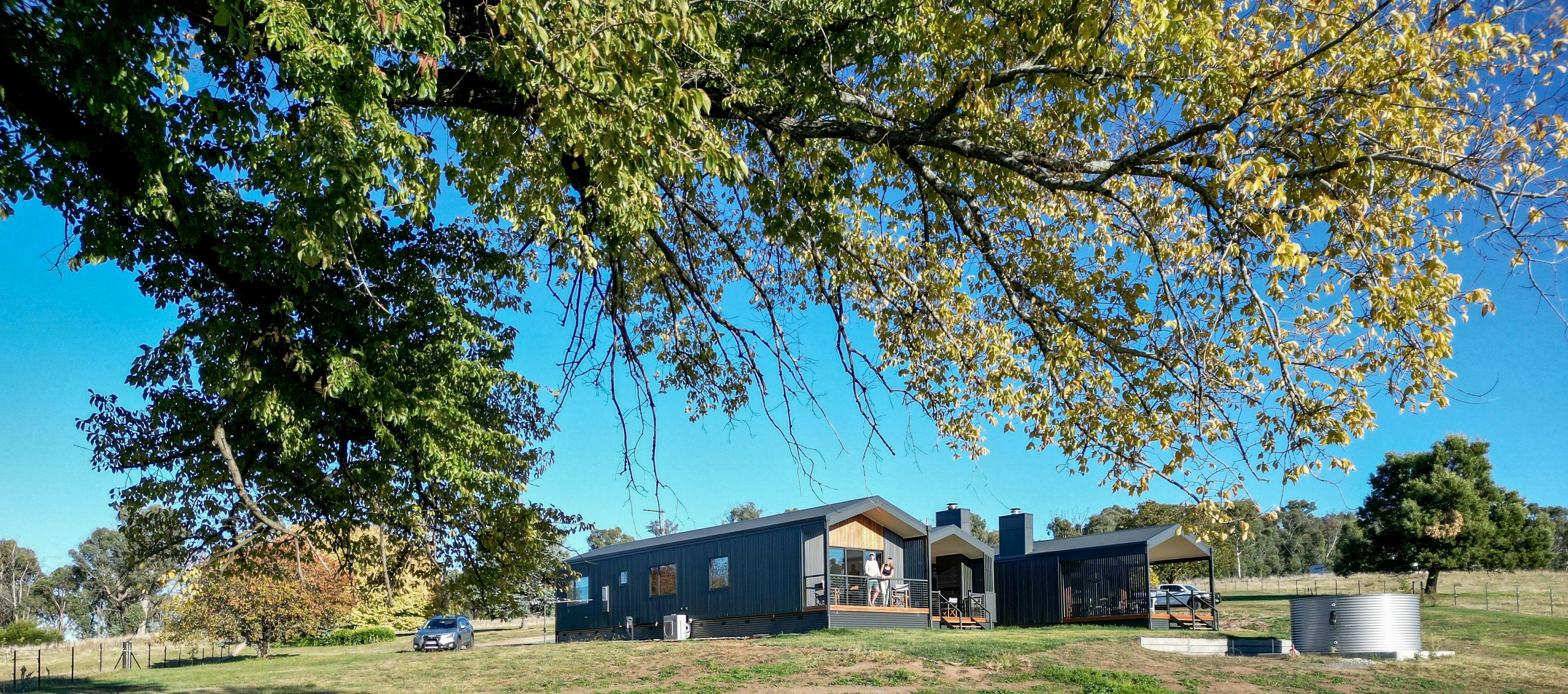 田園風景を見渡せるモダンなキャビンのプライベートバルコニーに立つ宿泊客たち。