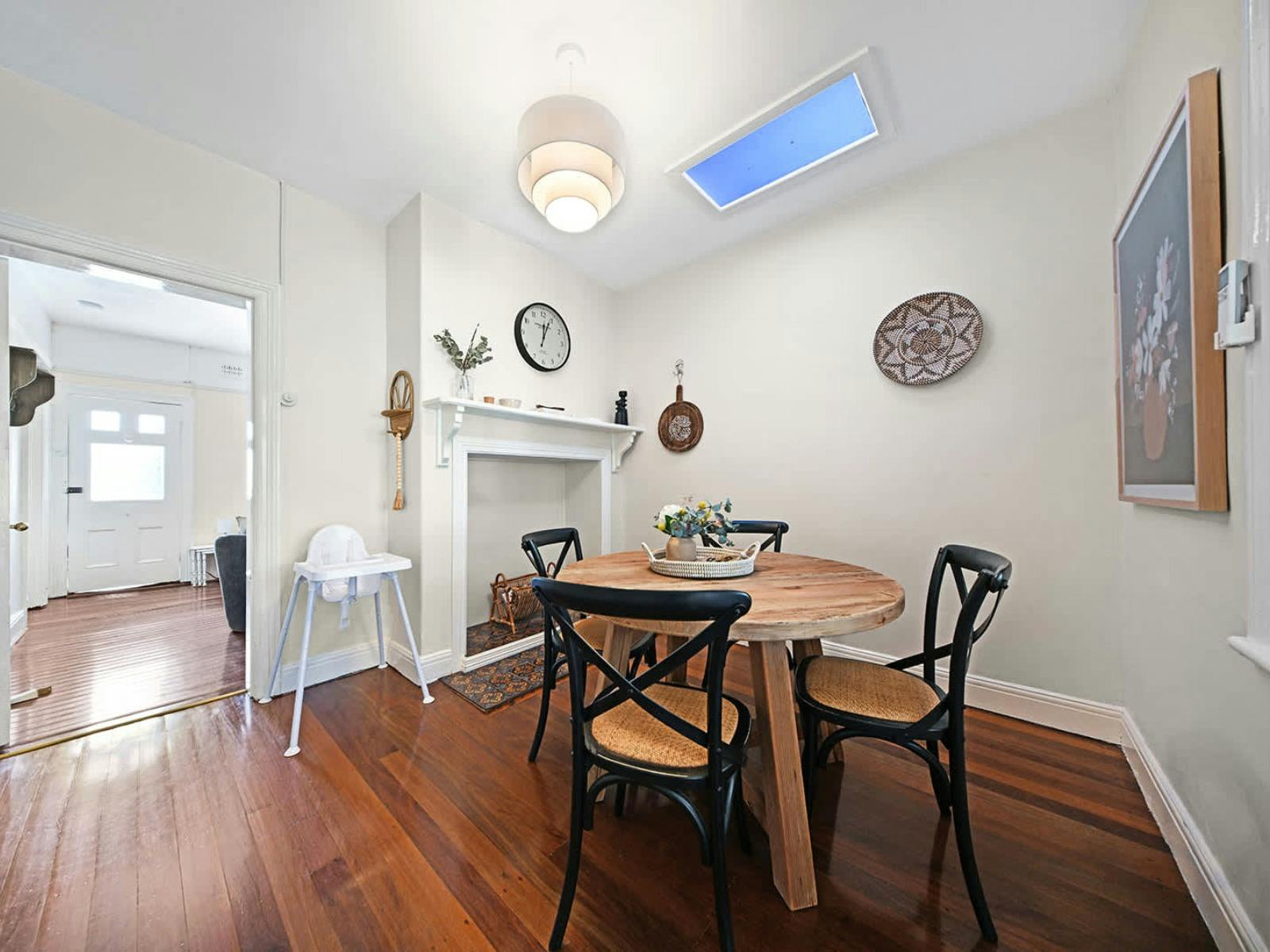Round dining table with 4 chairs, a sky light, wall decor and wooden floors