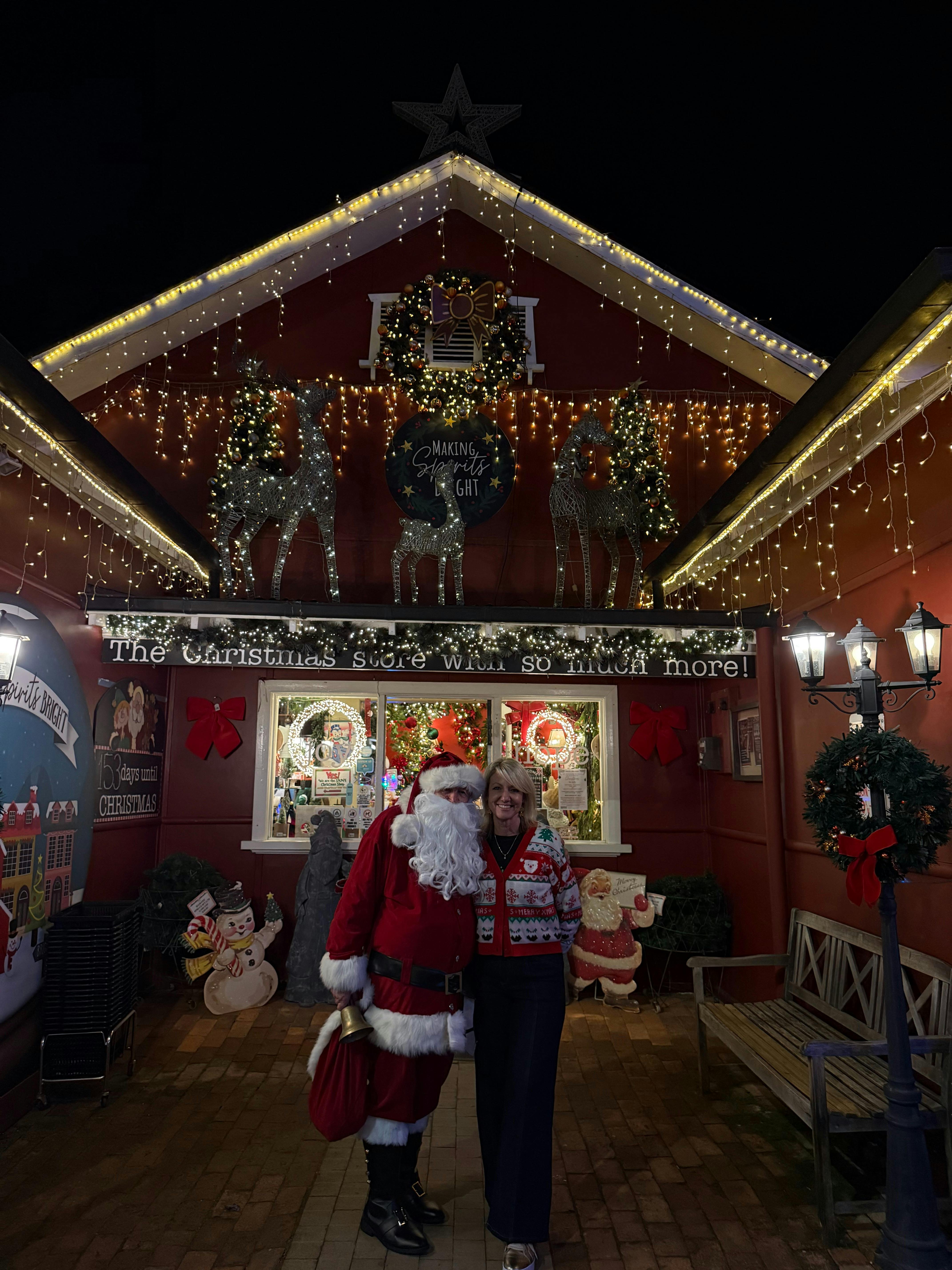 Amanda and Santa standing in front of the store Making Spirits Bright