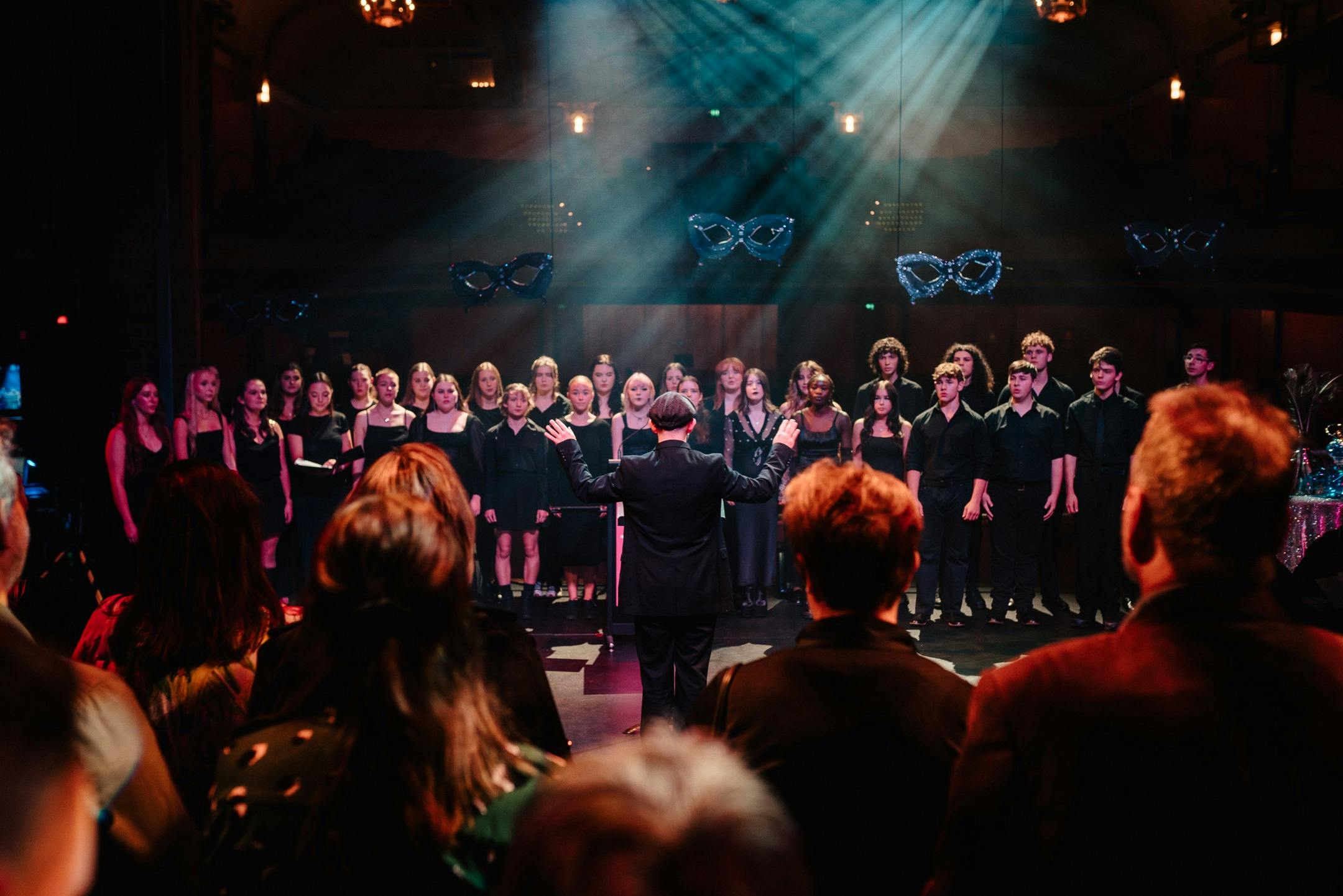 A choir of high school students dressed in black on stage