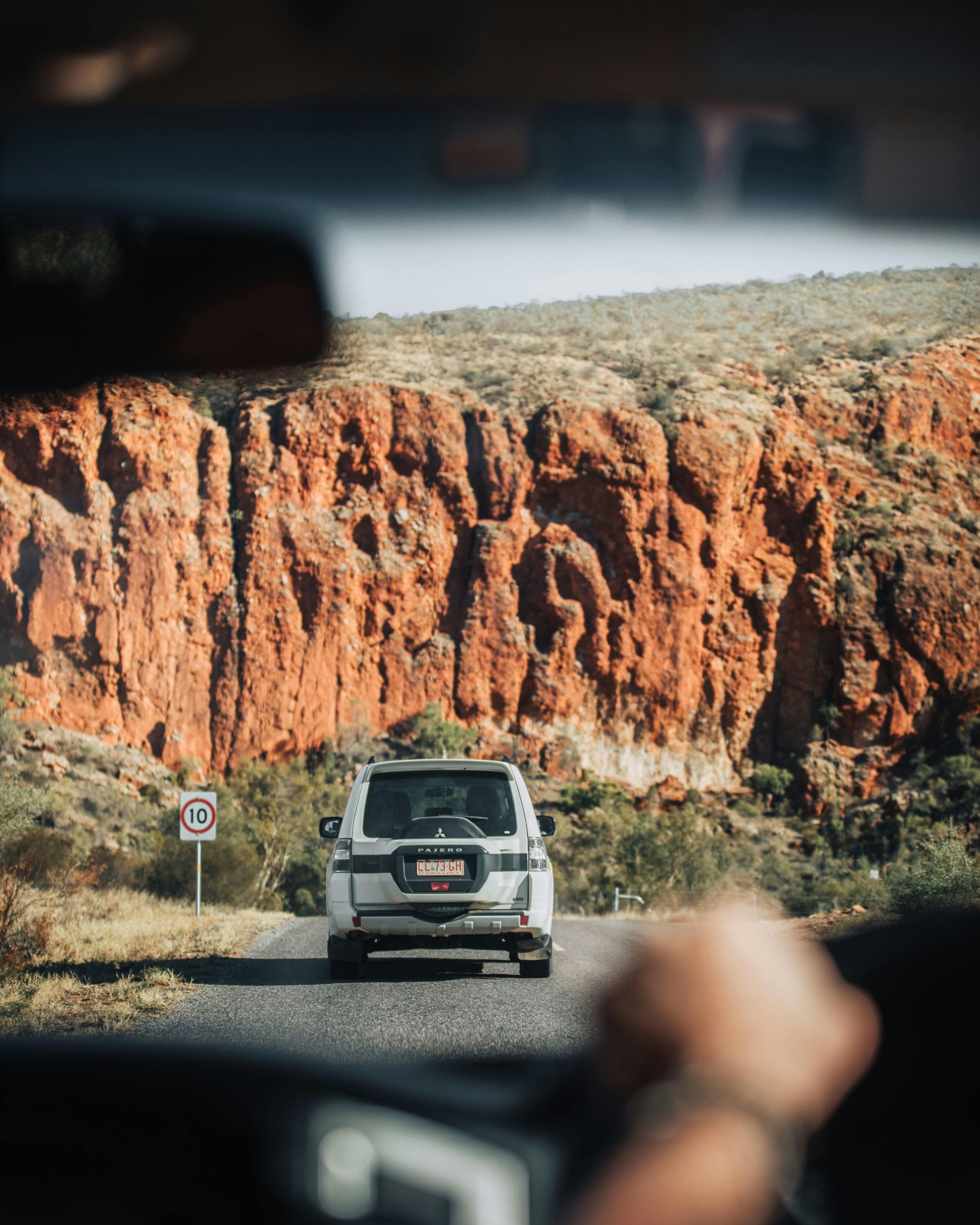 A 4WD driving towards the red cliffs near Redbank Gorge in the West MacDonnell Ranges