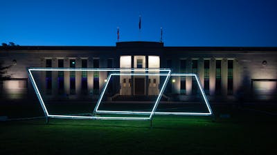 Neon light sculpture on the grass of the National Film and Sound Archive. Photo taken at night.