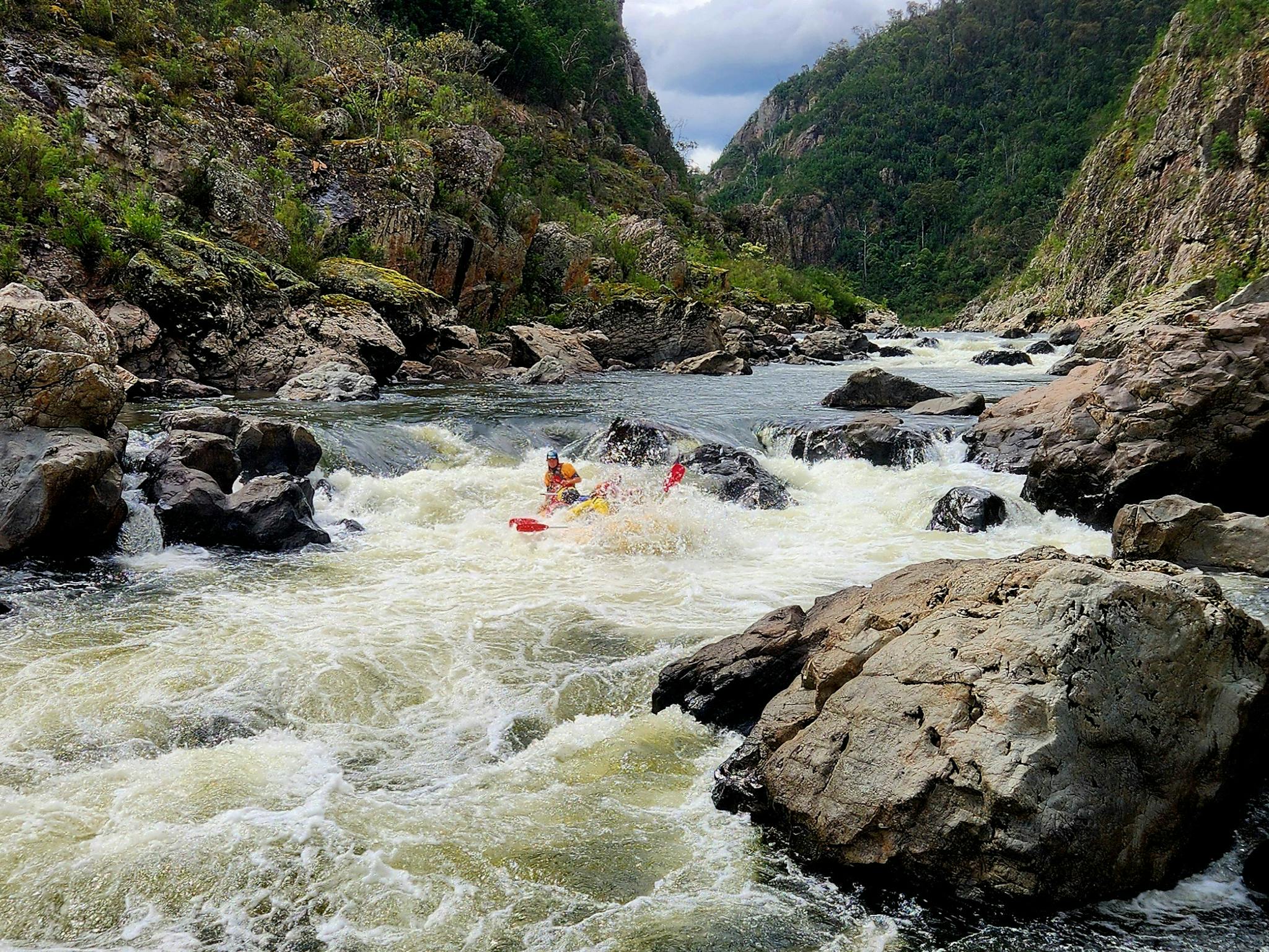 Yelloe whitewater raft on the Snowy River with clients obscured by wave crashing over them.