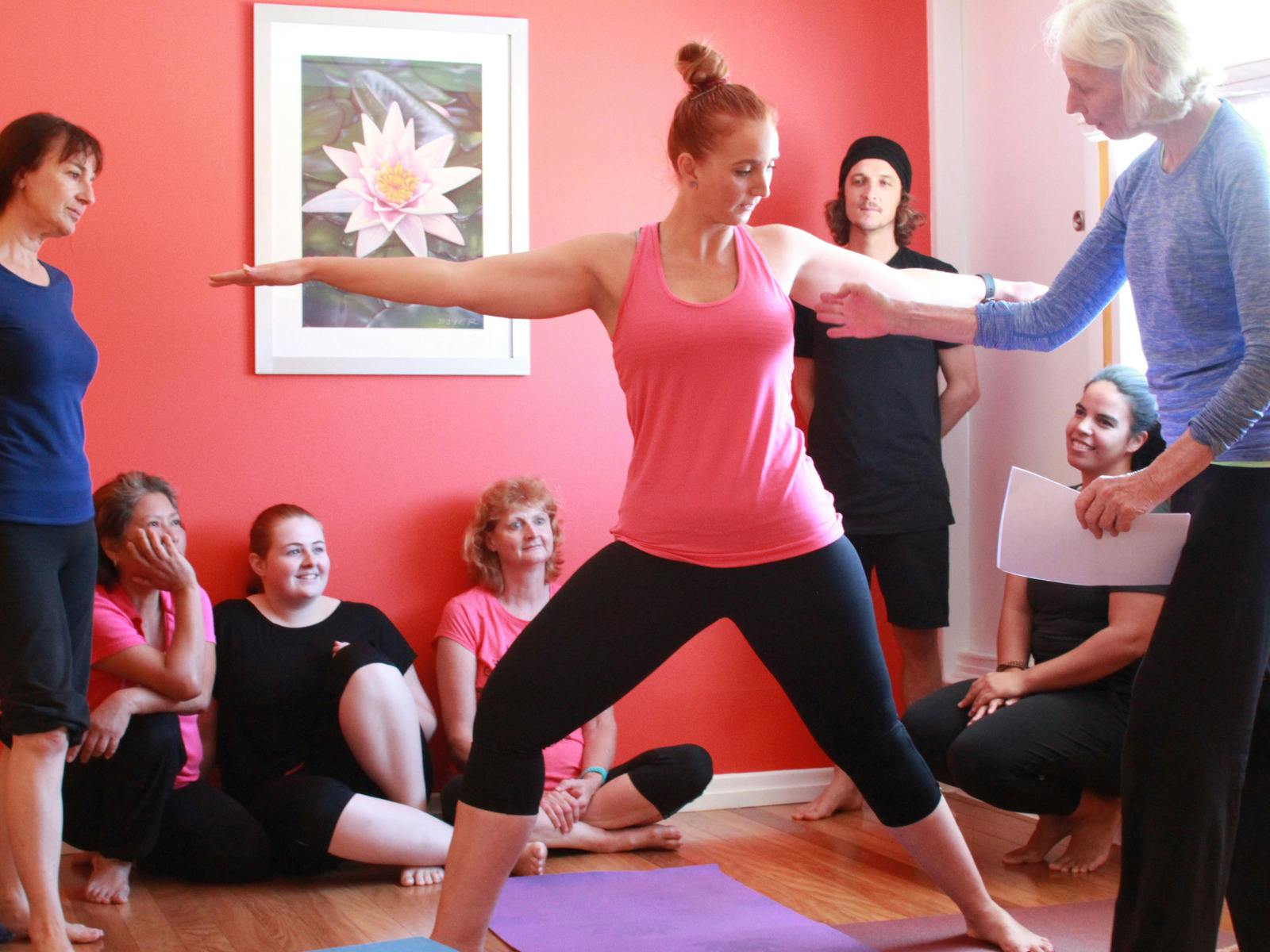 Group of people watching a yoga instructor show them how to correct postures