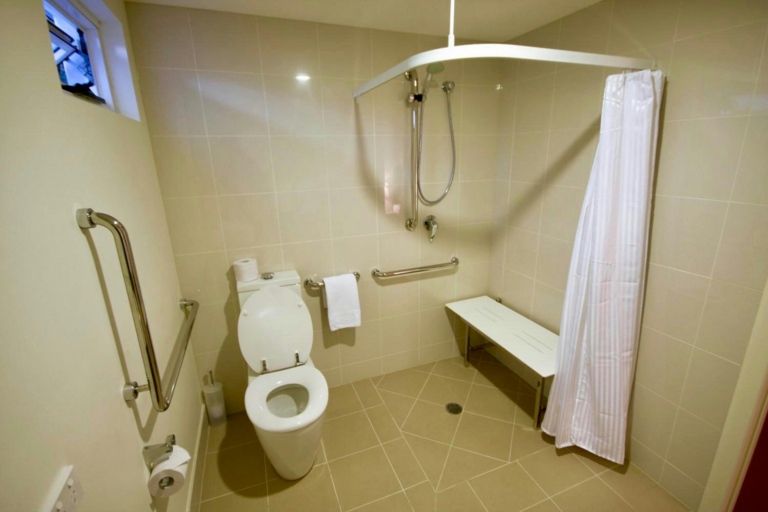 Wheelchair-accessible bathroom with grab rails and shower seat