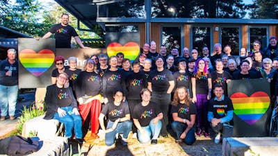 Picture of Canberra QWIRE people smiling and holding rainbow heart banners