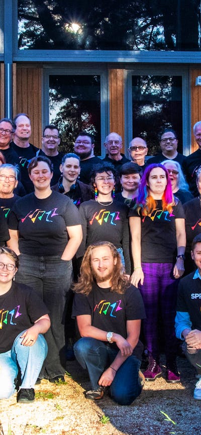 Picture of Canberra QWIRE people smiling and holding rainbow heart banners
