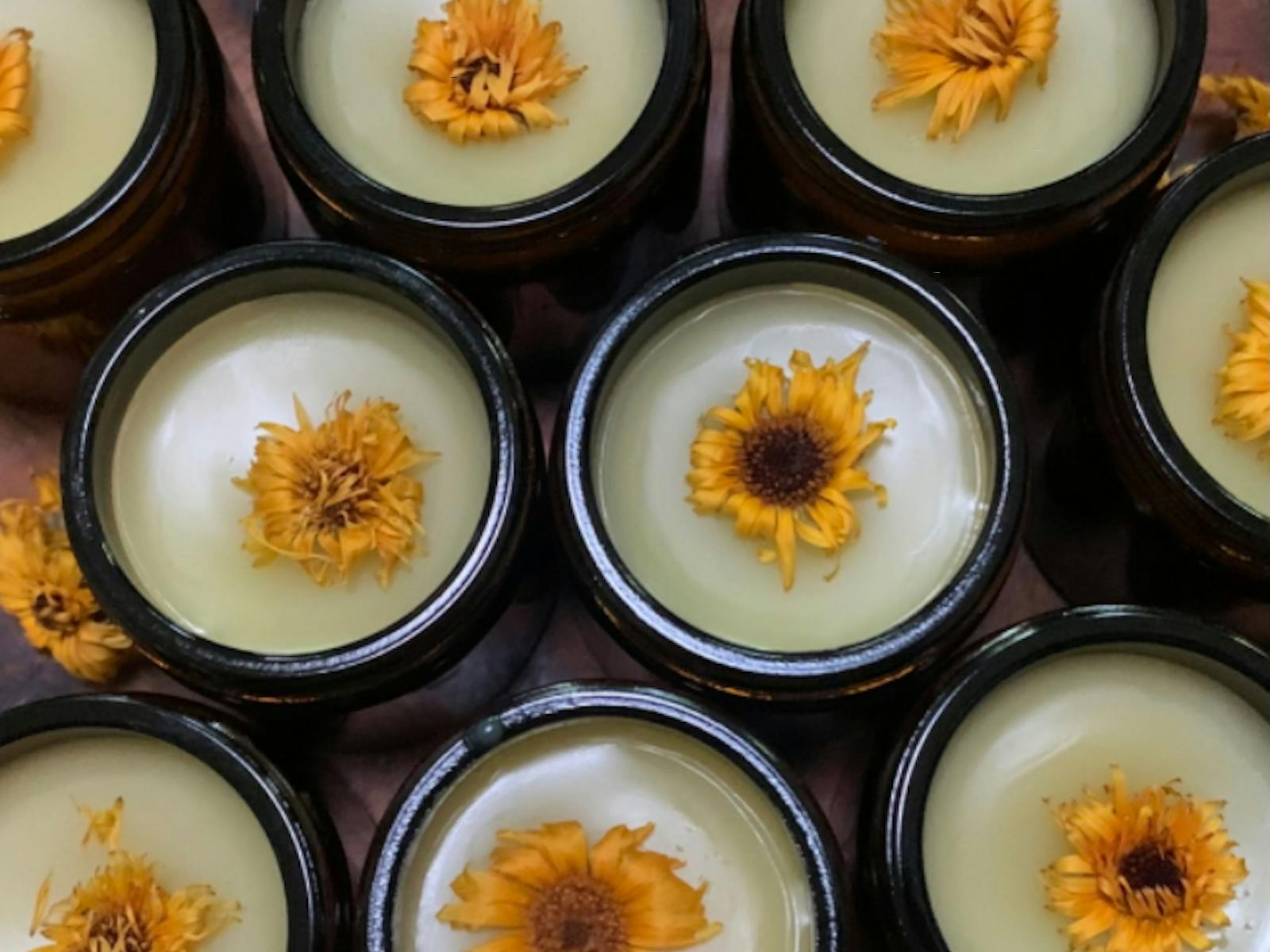Amber jars filled with calendula salve and dried flowers on top