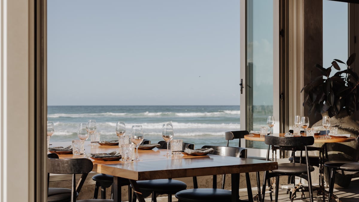 Tables at Rick Shores looking out onto the ocean through the open windoes