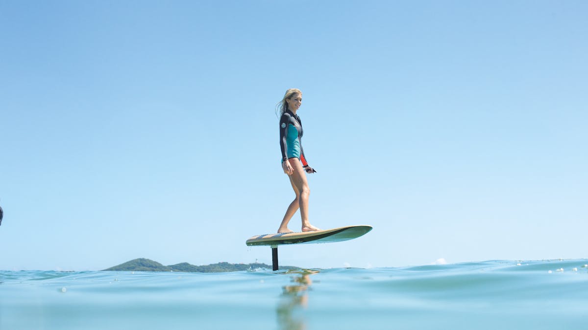 Woman eFoiling over calm blue water, smiling