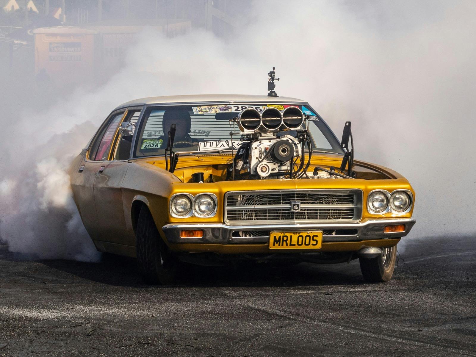 Gold supercharged burnout car MRLOOS driving through thick white tyre smoke.