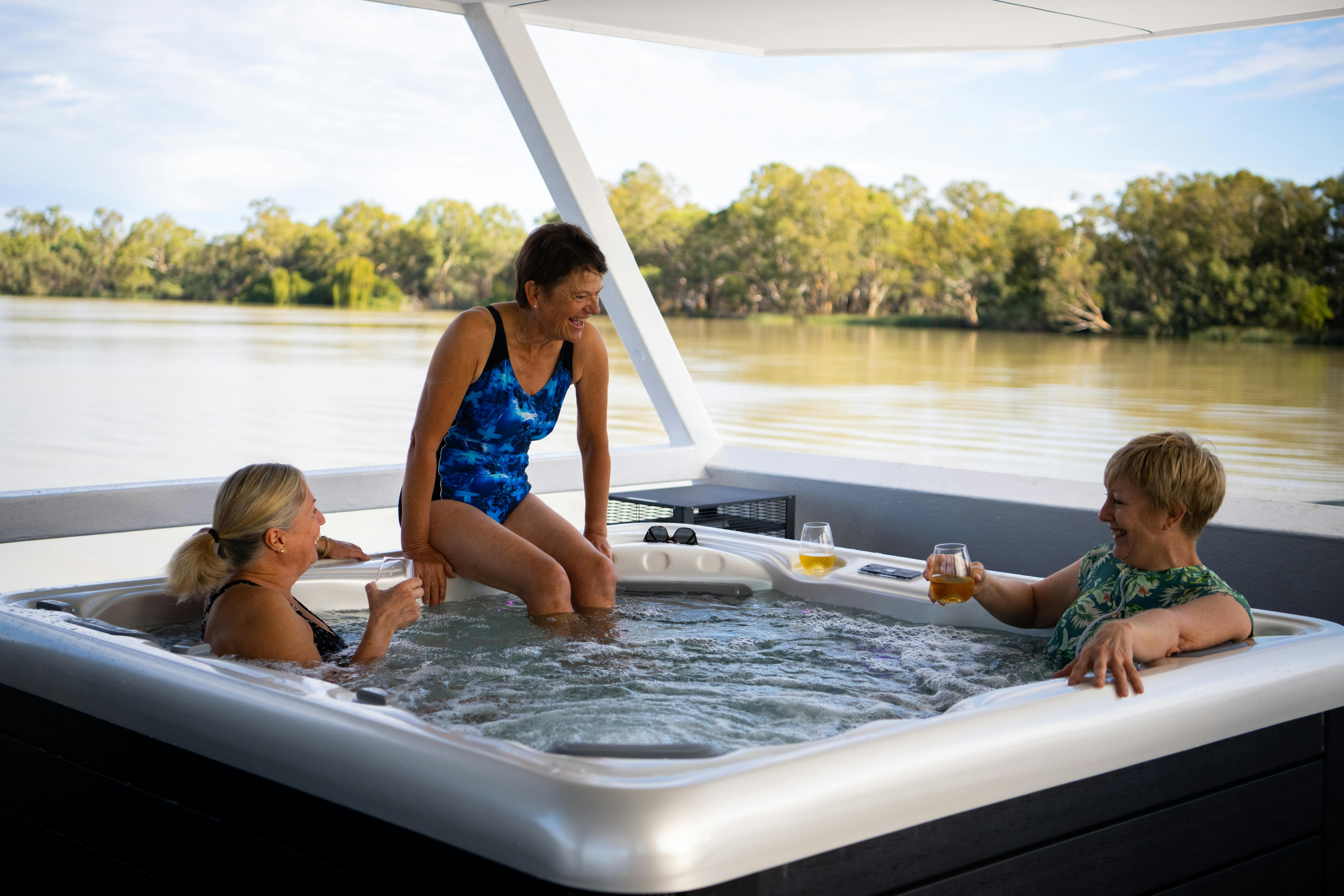 Three ladies have a spa on the upper deck of a houseboat with great views of the Murray River