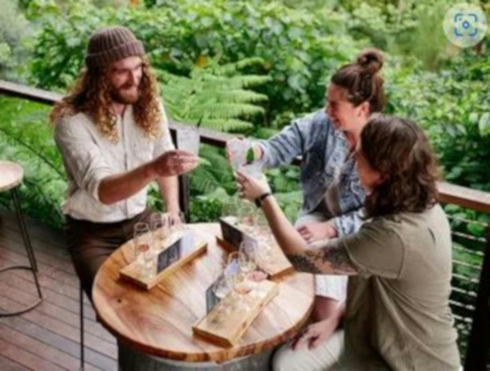 three people cheersing drinks at an outdoor bar