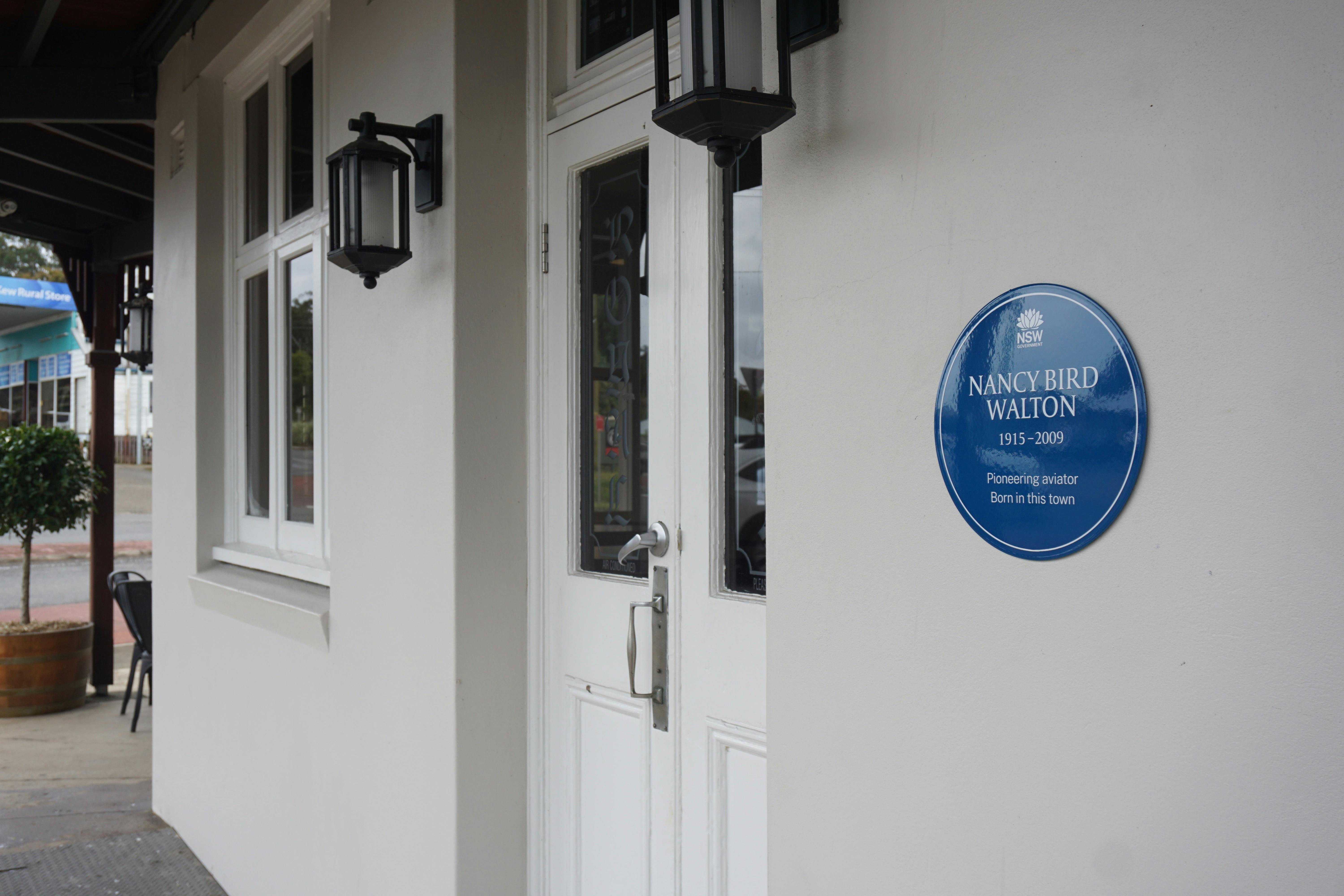 Blue plaque, white french door, window and coach lights on side of Royal Hotel,
