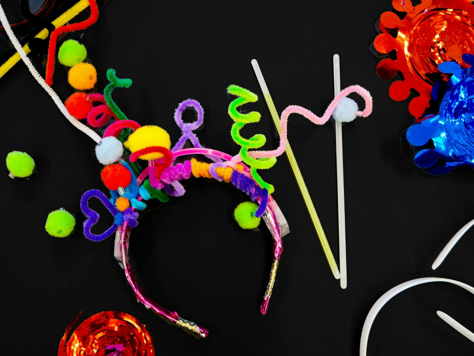 Rainbow pipe cleaners, glow sticks and other craft objects on black background