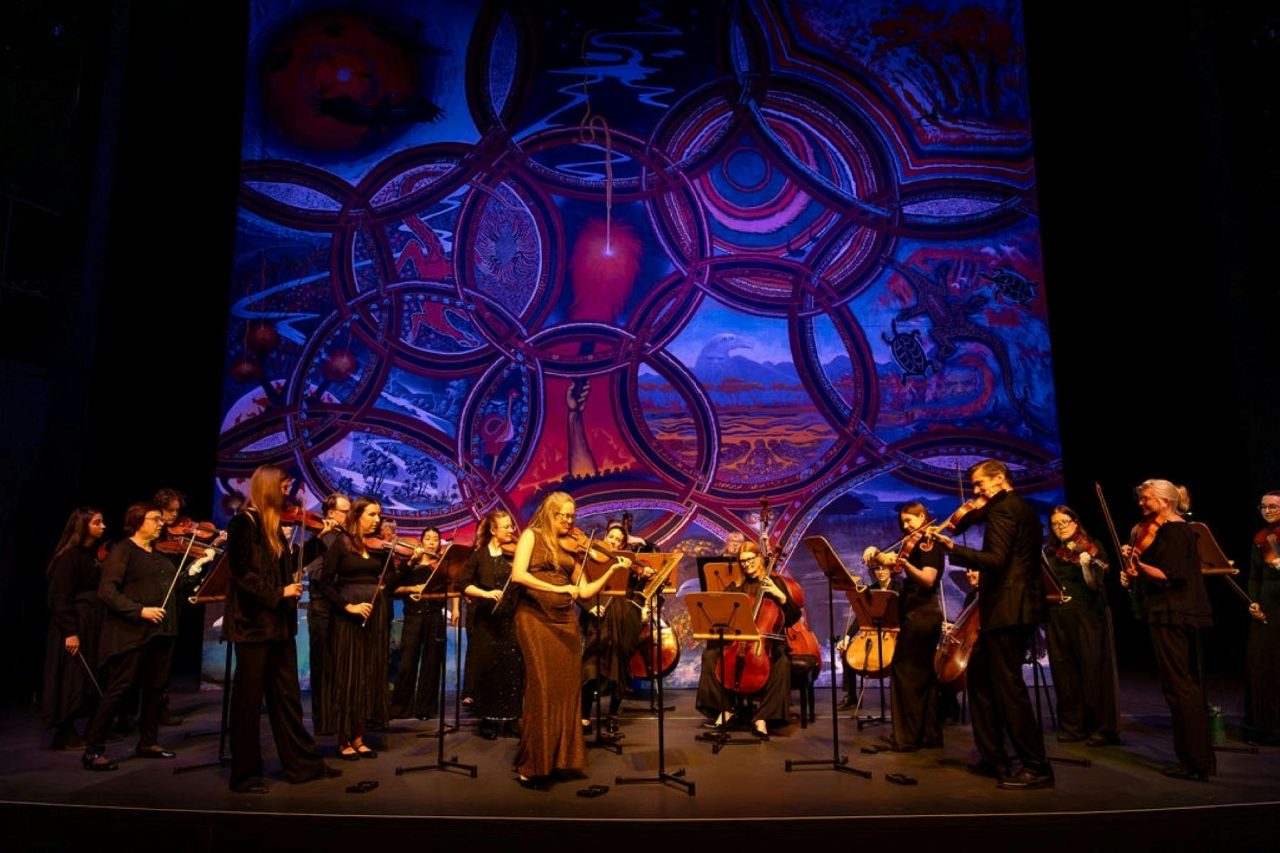 Full orchestra on stage taking a bow at the end of a performance