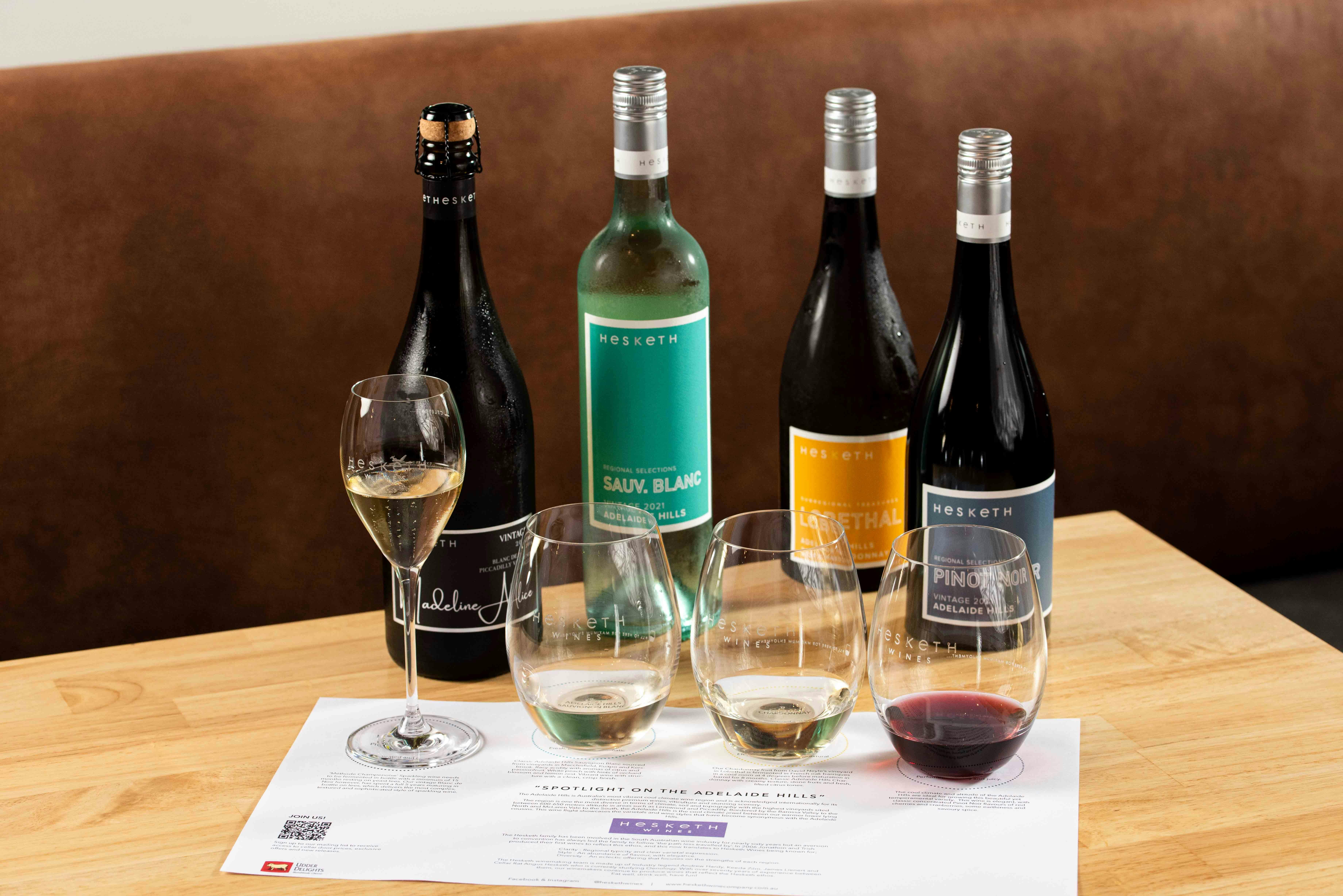 four bottles of wine poured into a wine flight tasting