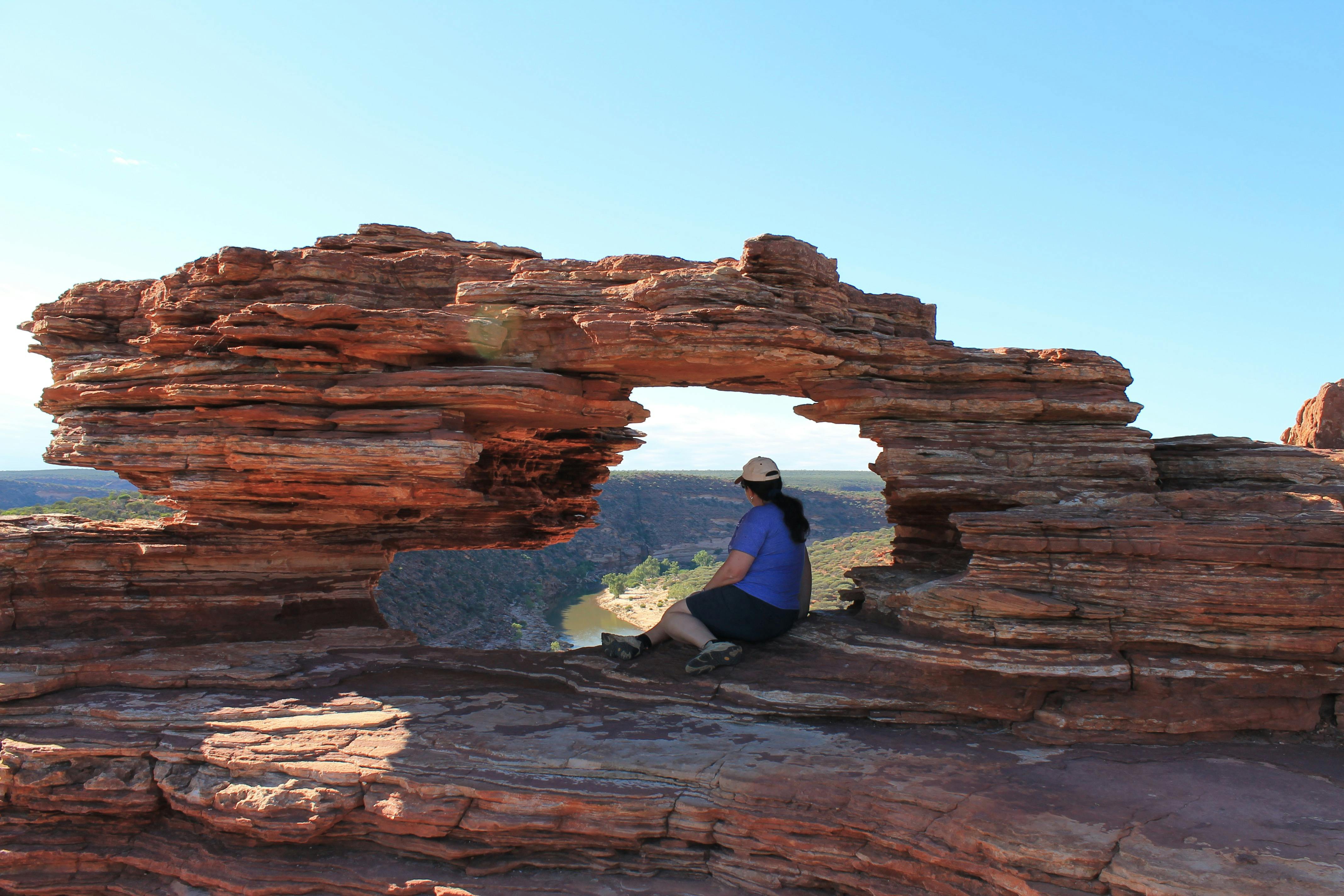 Woman sitting in a hole in the rock looking at views over a river